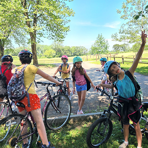 Kids stopped on their bikes along a trail. One is looking at the camera making a silly face.