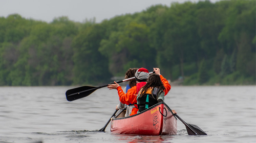 View from behind of people paddling on a lake