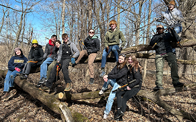 A group of youth sitting on branches of a large, fallen tree